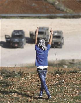 فلسطيني يرفع شارة النصر خلال مواجهات مع قوات الاحتلال قرب معتقل عوفر امس (ا ف ب)