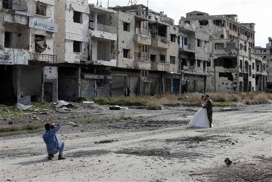 مصور يلتقط صورة لعروسين وسط شارع مدمر في حمص امس (ا ف ب)