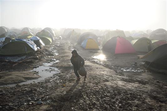  طفل يمشي قرب الخيم في مخيّم قرب بلدة ادوميني على الحدود اليونانيّة المقدونيّة، أمس (أ ف ب)