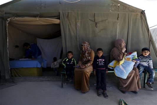 سيدتان سوريتان مع أطفالهما في مخيّم الزعتري للاجئين في الأردن (رويترز)
