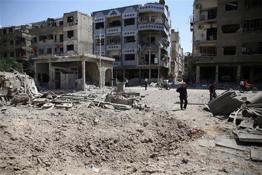 سوريون يتفقدون الأضرار جراء ضربة جوية في دوما في ريف دمشق أمس (رويترز)
