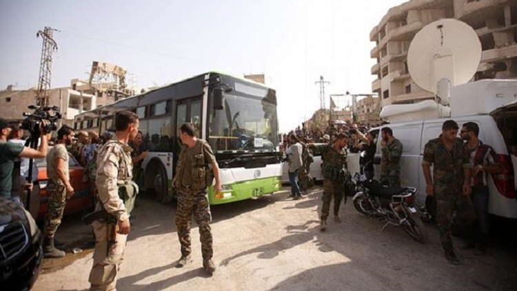 عنالصر من الجيش السوري قرب حافلة ركاب تجلي سكان داريا من المدينة