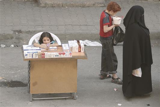 طفلة سورية تبيع السجائر في حي الشعار في حلب أمس (رويترز)