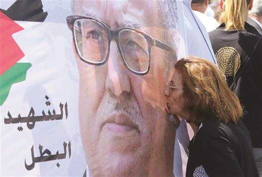متظاهرة تُقَبِّل صورة لناهض حتر خلال اعتصام تنديداً باغتياله أمام مقر الحكومة الأردنية في عمان أمس (أ ف ب)