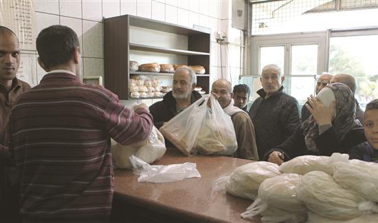سوريون ينتظرون دورهم لشراء الخبز في أحد الأفران في دمشق (عن الإنترنت)