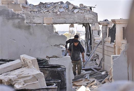 جنود سوريون يعبرون ركام المباني المدمرة في مشروع الـ»3000» شقة السكني في الحمدانية شرق حلب أمس (أ ف ب)
