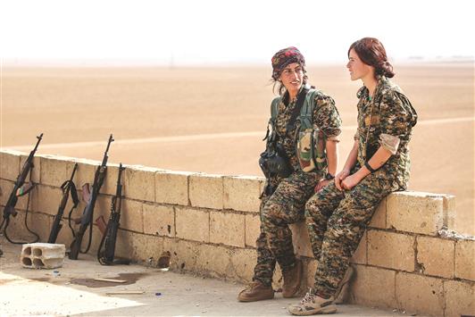 شيرين وكازيوار مُقاتلتان من وحدات «حماية الشعب الكردية» تتحدّثان من على سطح أحد المنازل في مزرعة خالد القريبة من الرقّة، أمس الأول (ا ف ب)
