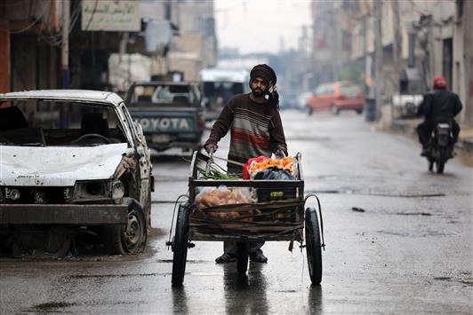 سوري يجرّ عربةً للخضار في أحد أحياء دوما في ريف دمشق أمس (أ ف ب)