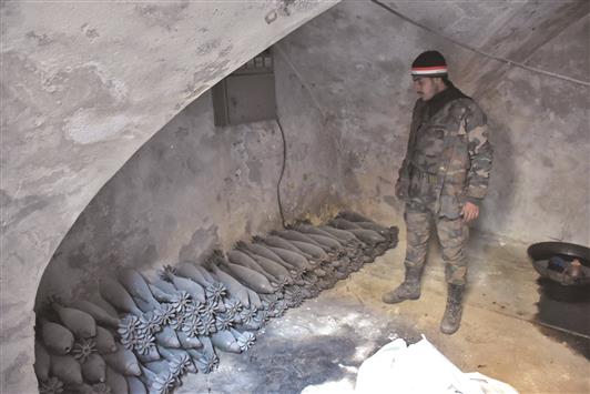 جندي سوري قرب قذائف «مورتر» مخزَّنة داخل غرفة في حي باب النصر بعد تحريره شرق حلب أمس (أ ف ب)