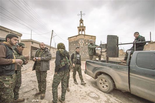مسلحون اكراد قرب كنيسة أشورية في قرية تل جمعة في ريف الحسكة أمس (رويترز)