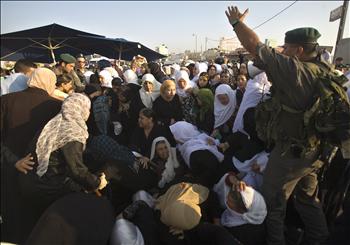 جندي للاحتلال يصرخ في وجوه فلسطينيات يجاهدن للعبور الى القدس المحتلة للصلاة في المسجد الاقصى عند حاجز قلنديا قرب رام الله أمس 