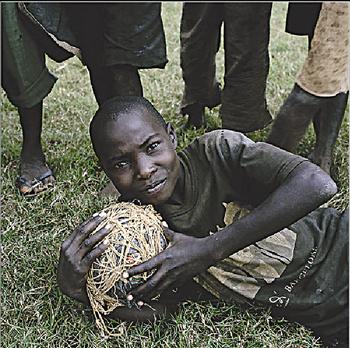 صبي من الموزمبيق يمسك بكرته المصنوعة من القش