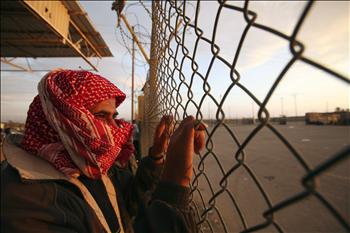 فلسطيني ينتظر أقرباء له وراء السياج الحدودي في معبر رفح أمس