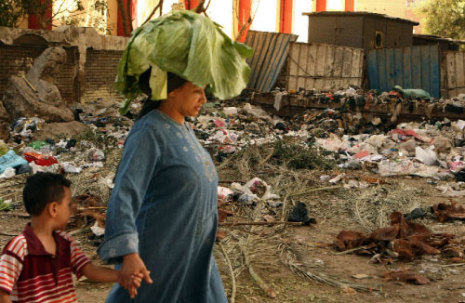 مصرية تسير مع طفلها بجوار اكوام من النفايات في احد شوارع القاهرة.