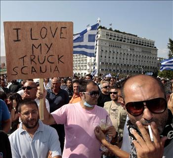 يوناني يرفع لافتة كُتب عليها «أنا أحب شاحنتي» خلال تظاهرة للسائقين أمام البرلمان اليوناني في أثينا أمس.