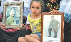 طفلة فلسطينية تحمل صورتي سجينين 