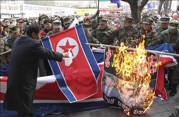 قدامى البحرية الكورية الجنوبية يحرقون صوراً لكيم جونغ إيل ووالده وابنه خلال تظاهرة في سيول أمس 