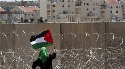 فلسطينية ترفع علم بلادها قرب جدار الفصل الجديد في بلعين قرب رام الله امس (ا ب ا) 