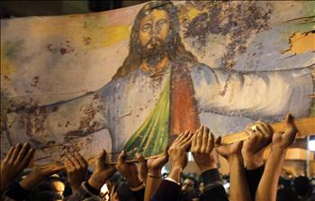 مصريون أقباط يحملون أيقونة ملطخة بالدماء للمسيح خلال تظاهرة أمام كنيسة القديسين في الاسكندرية مساء أمس الأول