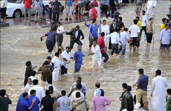 سعوديون يستخدمون حبلاً لعبور شارع غمرته السيول في جدة أمس