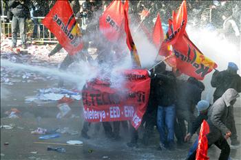 عمال وطلبة يحاولون الاحتماء بلافتات في مواجهة خراطيم مياه الشرطة في أنقرة أمس