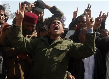 ثائر ليبي يبكي ويرفع شارة النصر خلال تشييع رفاق له استشهدوا خلال المعارك ضد قوات النظام في بنغازي أمس