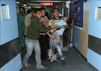 فلسطينيون يحملون فتى استشهد بقذائف دبابات الاحتلال إلى مستشفى الشفاء في غزة أمس