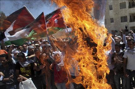 متظاهرون أردنيون يحرقون العلم الاسرائيلي أمام سفارة الدولة العبرية في عمّان أمس (رويترز) 