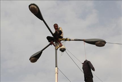 معارض يمني يشارك المطالبين بتنحي صالح احتجاجهم من فوق عمود للانارة في صنعاء امس (رويترز) 
