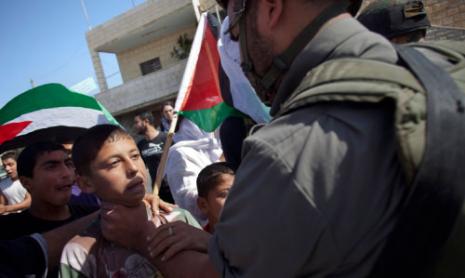 جندي إسرائيلي يعتدي على فتى فلسطيني في بلدة بيت عمر في الضفة الغربية المحتلة أمس (برنات أرمانغ ــ أ ب) 