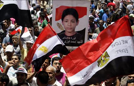 متظاهرون مصريون يرفعون أعلاماً وصورة لأحد شهداء الثورة في ميدان التحرير في القاهرة أمس (أ ب أ) 