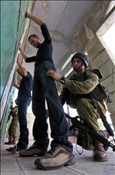 جندي احتلال إسرائيلي يفتش فلسطينيين في مدينة الخليل في الضفة الغربية المحتلة أمس 