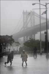 أميركيون يعبرون في منطقة غمرتها المياه من أجل التقاط الصور بالقرب من جسر مانهاتن في نيويورك التي ضربها إعصار «ايرين» أمس. (أ ب) 