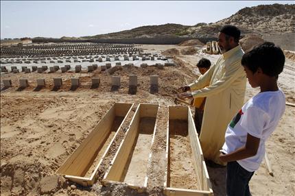 ليبيون قرب مقبرة يُدفن فيها أتباع القذافي في مصراتة أمس (رويترز) 