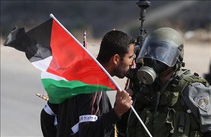 فلسطيني يواجه جنديا اسرائيليا خلال تظاهرة ضد توسيع المستوطنات في قرية النبي صالح في الضفة الغربية امس (ا ف ب) 