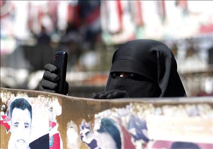 يمنية تلتقط الصور بواسطة هاتفها الخلوي خلال مشاركتها في احتجاج في ساحة التغيير في صنعاء امس (رويترز) 