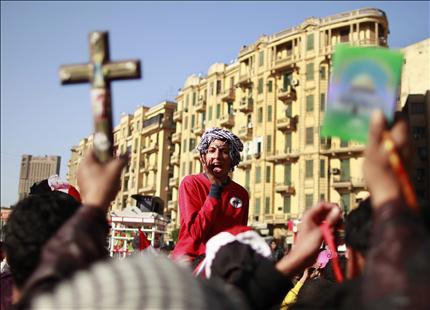 متظاهر يحمل صليباً ومصحفاً خلال مسيرة في ميدان التحرير في القاهرة أمس (رويترز) 