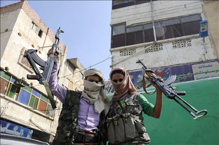 يمنيان معارضان يرفعان سلاحهما خلال مشاركتهما في تظاهرة تطالب بمحاكمة صالح في تعز امس (رويترز) 