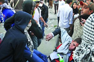 يخلون جريخاً أصيب خلال المواجهات مع الشرطة قرب مبنى وزارة الداخلية في القاهرة أمس (رويترز). 
