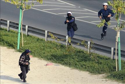 شرطي بحريني يصوب سلاحه نحو مصور صحافي قرب مقر «الوفاق» في إحدى ضواحي المنامة أمس (أ ف ب) 