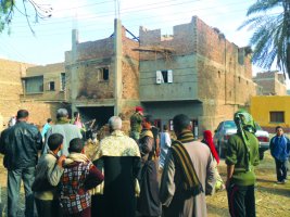 رجال أمن ومواطنون أمام منزل متضرر جراء المواجهات بين الأقباط والمسلمين في أسيوط 