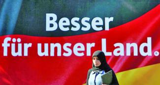 محجبة تمر أمام علم ألماني كتب عليه (الأفضل لبلادنا) خلال حملة مناهضة للحجاب 