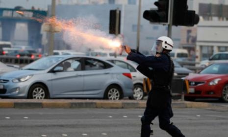 شرطي يطلق قنابل غاز مسيلة للدموع في أثناء المواجهات التي أعقبت تشييع صلاح عباس (حمد أ. محمد ـ رويترز)