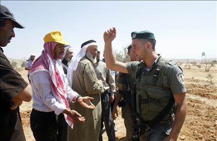 جندي إسرائيلي يمنع مزارعين فلسطينيين من العمل في أراضيهم في بلدة تقوع شرقي بيت لحم أمس (أ ف ب) 