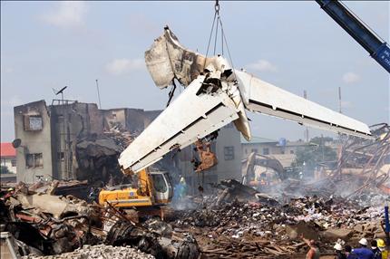 فرق الإنقاذ ترفع جزءاً من الطائرة في مكان الحادث في لاغوس في نيجيريا أمس (أ ف ب) 