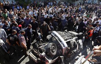 فلسطينيون يتجمعون حول سيارة دمرتها طائرات الاحتلال الإسرائيلي لاغتيال   ناشط في غزة أمس