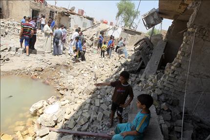 عراقيون يقفون بين ركام منازل مدمرة في شمال بغداد أمس (أ ف ب) 