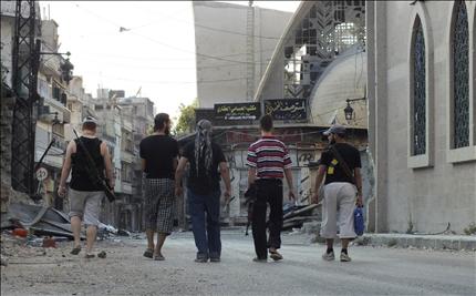 مسلحون يتجولون في أحد أحياء حمص أمس (رويترز) 