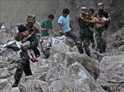  جنود يحملون أطفالاً خلال عمليات الإغاثة من الزلزال في إقليم يونان في جنوب غرب الصين أمس. (رويترز) 