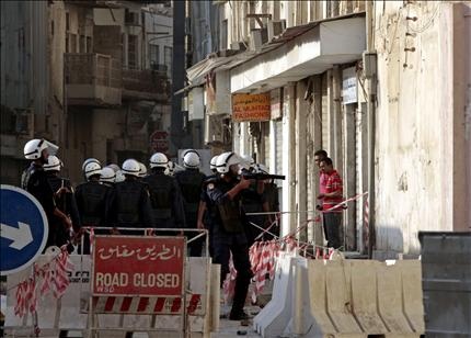  عنصر من الشرطة يطلق قنبلة غاز على المتظاهرين في المنامة أمس (أ ب) 